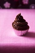 Schokoladen-Cupcake mit Schokoladecreme auf lila Untergrund