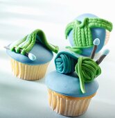 Drei Cupcakes mit blauer Glasur und Strick-Dekoration aus Marzipan