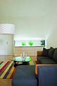 Simple corner sofa and classic coffee table on striped rug in minimalist living room