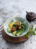 Meatballs with sesame seeds on a bed of vegetables served with noodles