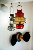 Different vintage paraffin lamps hanging from hooks in underside of wooden beams