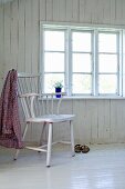Shirt hung over back of chair in plain room with white-painted wooden floor