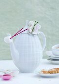 White, retro china coffee pot with fabric butterfly next to plate of biscuits