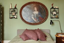 Traditional portrait of woman and wall racks of memorabilia above French bed