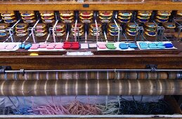 View of old Jacquard loom with finished ribbons emerging from bottom