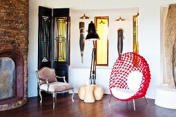 Ethnic artworks and designer chairs next to fireplace in rustic brick wall