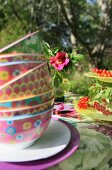 Gestapelte bunte Schalen auf einem sommerlichen Tisch im Garten