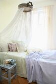 Single bed with canopy next to window in bedroom