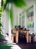 Modern, rustic table and benches on roofed terrace of residential house