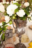 A bouquet of white roses in an old-fashioned silver vase as a table decoration