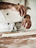 A chef dusting gnocchi dough with flour