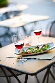 An aperitif of red wine with anchovy and mozzarella on salad leaves