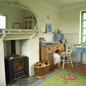 Interior with half-height wooden panelling, various old, wooden furnishings and ornate mirror above log burner in fireplace