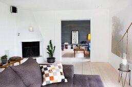 Patterned cushion on grey sofa in living room with corner fireplace and wide open doorway