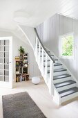 White, wood-panelled foyer with open-plan staircase in country house