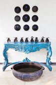 Collection of vintage miniature vehicles on blue console table below objet d'art on wall