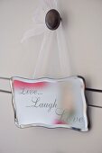 Silver sign with motto 'Live Laugh Love' hanging on drawer knob