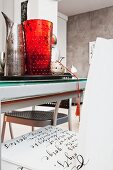Tablett mit originellen Gefässen auf modernem Esstisch und Schriftenmalerei auf einem Stuhl