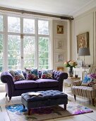 Purple sofa, ottoman and armchair in front of living room window