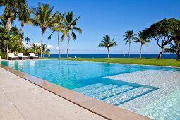 Blick über die Stufen eines langgestreckten Pools auf Palmen und Karibisches Meer