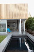 Contemporary house with open terrace door behind stone-edged pool
