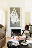 Colonial-style armchair and chair behind books and magazines on table in front of fireplace in partition below modern artwork