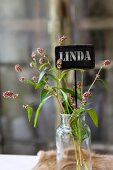 Wild flowers and name tag in vintage glass jar