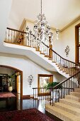 Spacious foyer with winding staircase and view of potted plant in hallway through arched doorway with wooden frame