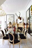 Postmodern chairs around mirrored table in dining room with stag's head and large collection of ornaments