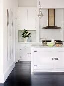 White fitted kitchen with retro elements and black wooden floor