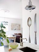 View over kitchen island into interior with dining area; tap fittings and retro-style pendant lamp