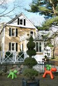 Amerikanisches Holzhaus mit Anbau und farbige Spielgeräte im Garten