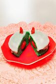 A green muffin with raspberries on a red plate