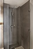 Modern shower area with grey tiles and open glass door