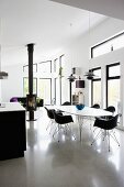 Essplatz mit schwarzen Schalenstühlen an weißem Tisch in offenem modernem Wohnraum