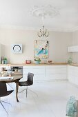 Antique dining table and modern chairs in renovated kitchen with stucco elements on walls and ceiling
