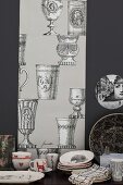 Crockery on table in front of strip with pattern of trophies on black wall