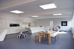 Child on tricycle in minimalist interior with dining area and futuristic counter