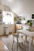 Bright, white kitchen-dining room with wooden base units and classic Scandinavian chairs