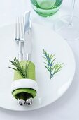 A plate decorated with a rosemary motif and a napkin ring decorated with a sprig of rosemary