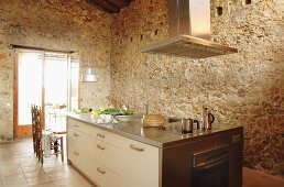 Modern kitchen island in front of rustic stone walls of converted, Spanish country house