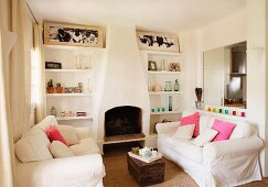 Comfy living room furniture with white slip covers in front of an open fireplace and brick, built in bookshelves with a rustic air