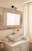 Modern sink on a vintage vanity and nostalgic, framed mirror next to a shower curtain