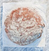 A loaf of bread on paper, on a marble slab, dusted with flour