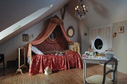 Romantic, feminine attic bedroom with Rococo canopy above bed and white-painted dressing table