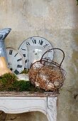 Old clock faces and wire basket of eggs on Rococo console table as romantic country house decoration