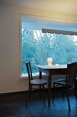 Simple dining table and chairs in front of window element with fixed glass panel