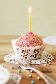 Cupcake mit bunten Zuckerperlen und einer Kerze