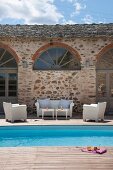 Terrasse mit weissen Outdoormöbeln und Pool vor mediterranem Haus