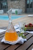 Set terrace table - refreshing drink in crystal carafe and glass on white linen napkin